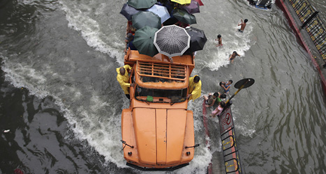 En lastbil full av människor korsar en översvämmad gata i Filippinernas huvudstad Manila. Foto: Aaron Favila/AP/Scanpix.